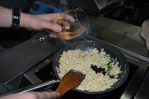 Готувати рис на слабкому вогні, постійно помішуючи, через 3-4 хвилин влити вино